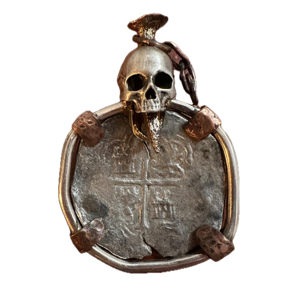 This one of a kind pendant contains a silver pirate skull with a copper nail through its head and a 8 Reale pirate silver coin! Designed and created by world, famous U-boat, hunter, Darrell Miklos