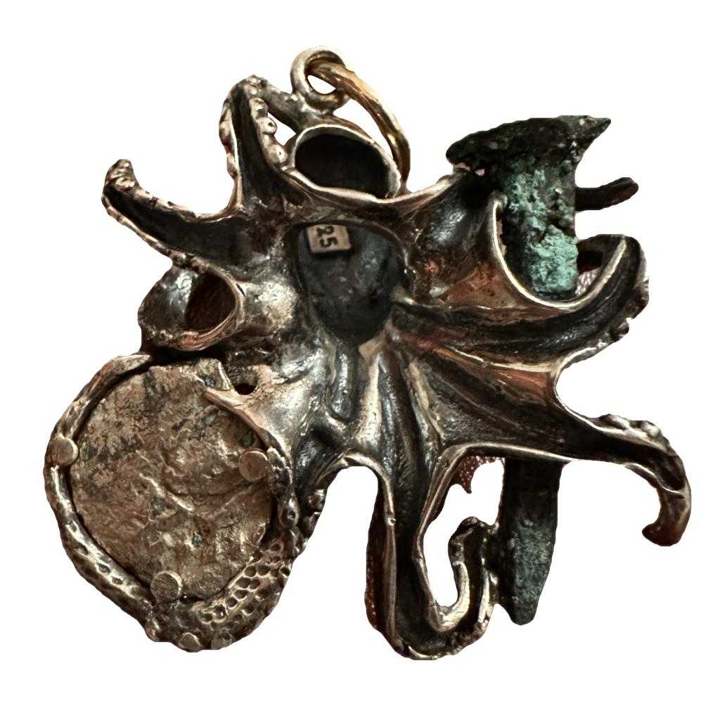 This is the backside of a handcrafted sterling silver octopus pendant with a 1/4 Reale silver coin, and a shipwreck copper nail. This pendant was designed and crafted by famous U-boat hunter, Darrell Miklos.