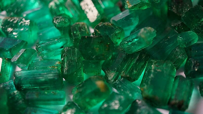 This is a picture of a large group of vibrant green raw emeralds, taken using a professional camera.